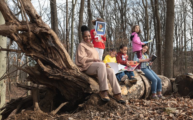 Students reading on a fallen tree during an outdoor session